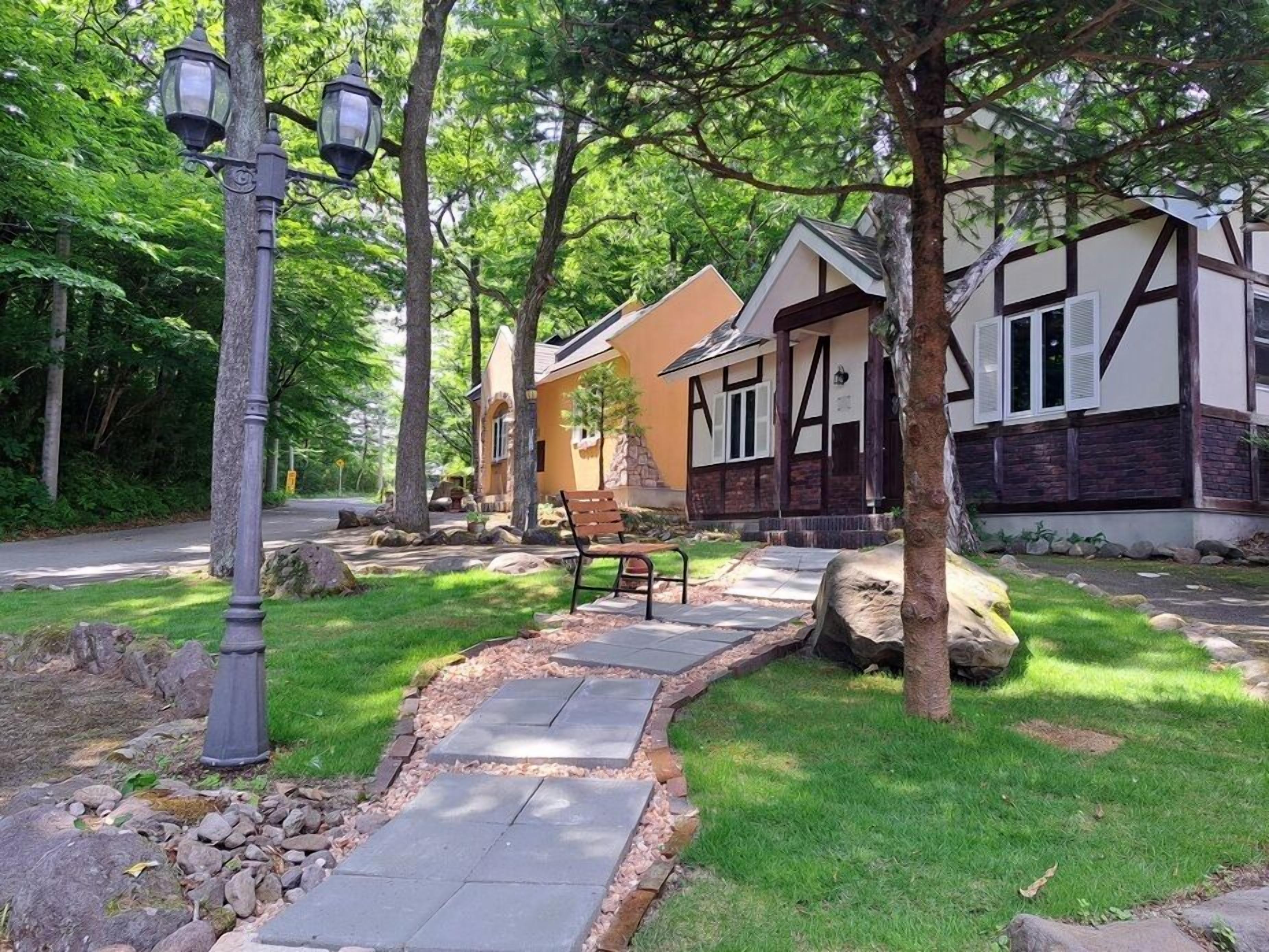 A residential property with a stone pathway, a bench, and two houses with distinct architectural styles.