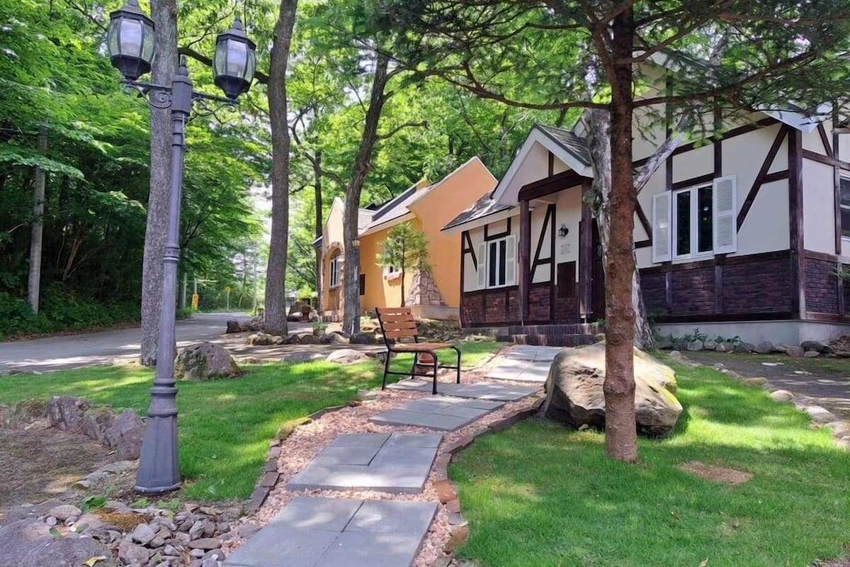 A residential property with a stone pathway, a bench, and two houses with distinct architectural styles.