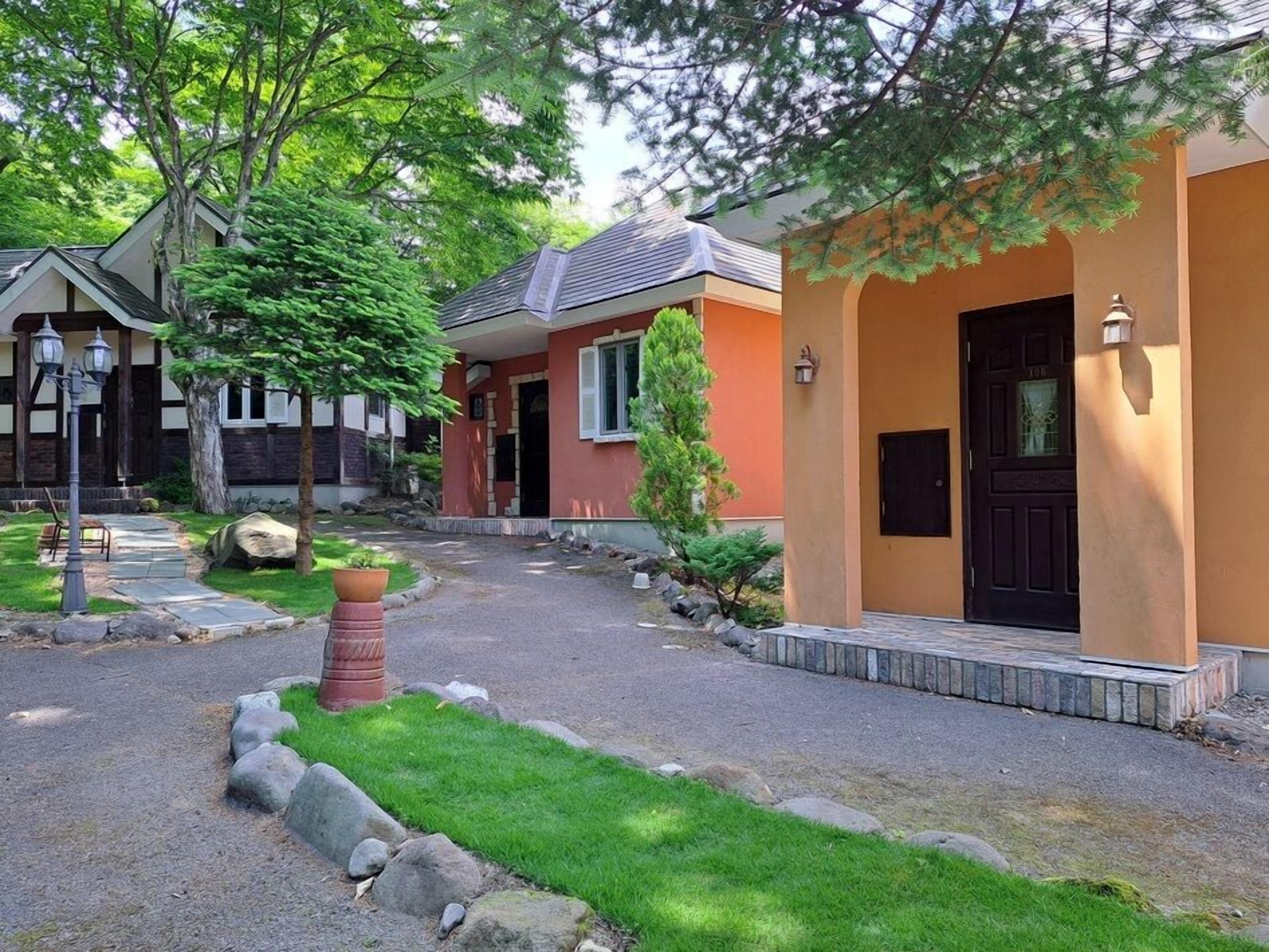 A residential area with houses featuring a mix of architectural styles, a paved driveway, and a well-maintained lawn.