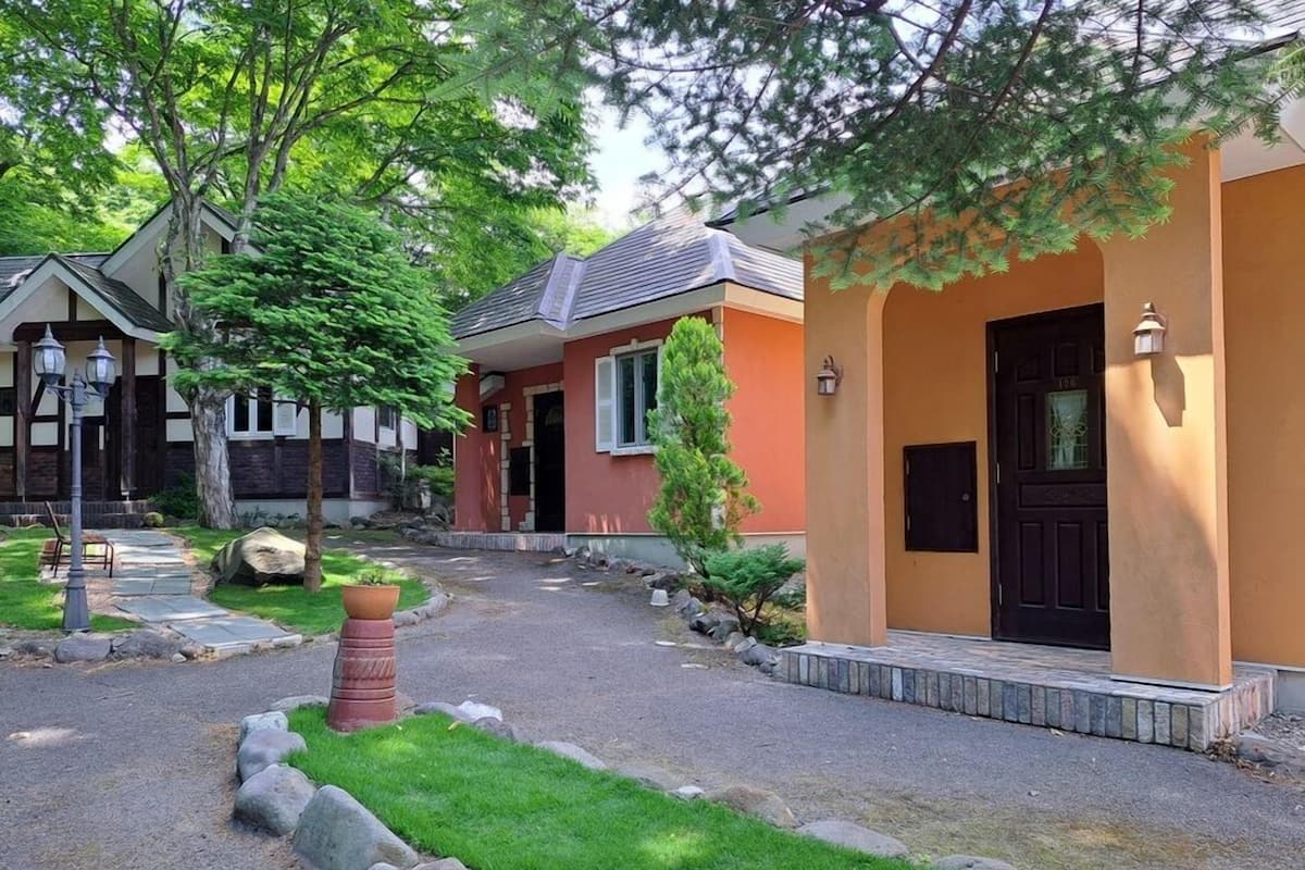 A residential area with houses featuring a mix of architectural styles, a paved driveway, and a well-maintained lawn.