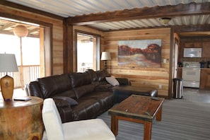 A cozy living room with a leather sofa, a wooden coffee table, and a painting on the wall. - Laguna Vista Tree House, Cloud Lane (New Braunfels)