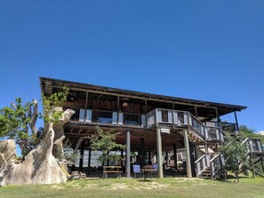 A wooden building with a balcony and outdoor seating area. - Laguna Vista Tree House, Cloud Lane (New Braunfels)