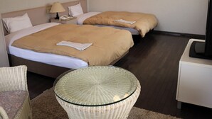 Une chambre d’hôtel avec deux lits, une petite table, une chaise et un téléviseur.