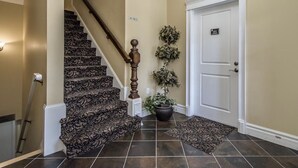 A staircase with patterned carpet, a white door with a number plaque, and a potted plant. - Windmill walk (Dartmouth)