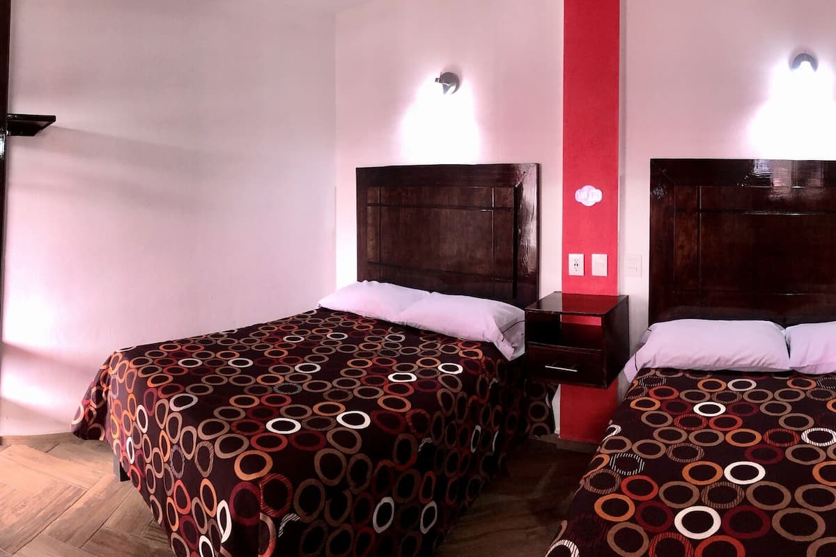 A hotel room with two beds, a TV, a desk, and a bathroom.