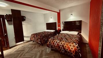 Habitación de hotel con dos camas, piso de madera y una pared de acento roja.