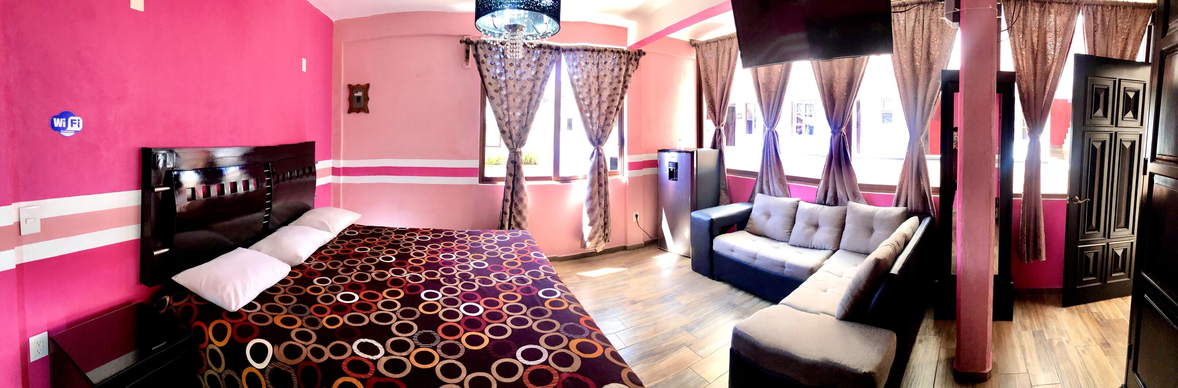 Una habitación de hotel con una cama, un sofá y cortinas.