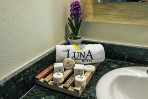 A bathroom counter with a towel, a potted plant, and a tray with jars labeled "La Luna Hotel". - Hotel La Luna (Mexico City)