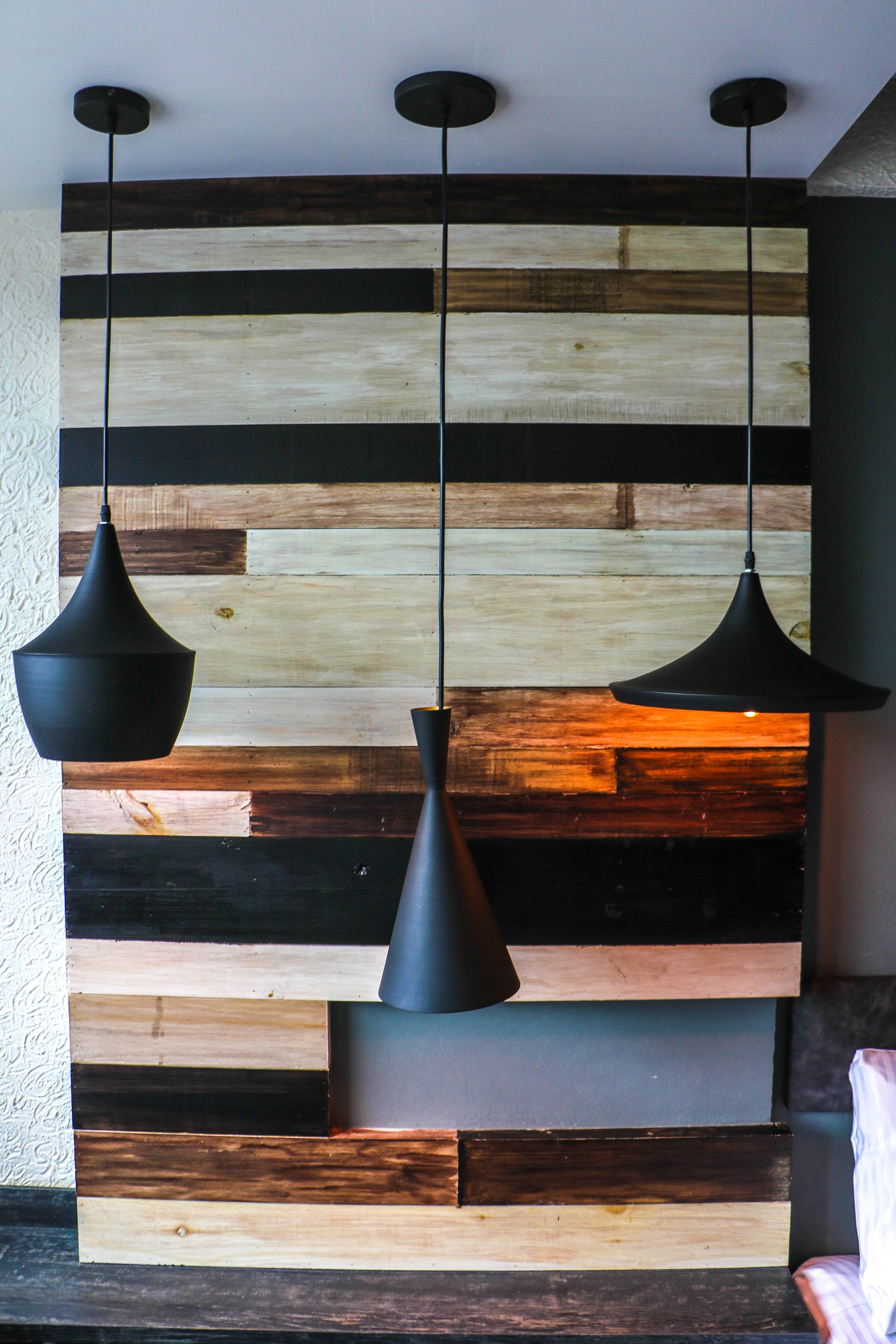 A wall with horizontal wooden planks and three black pendant lights.