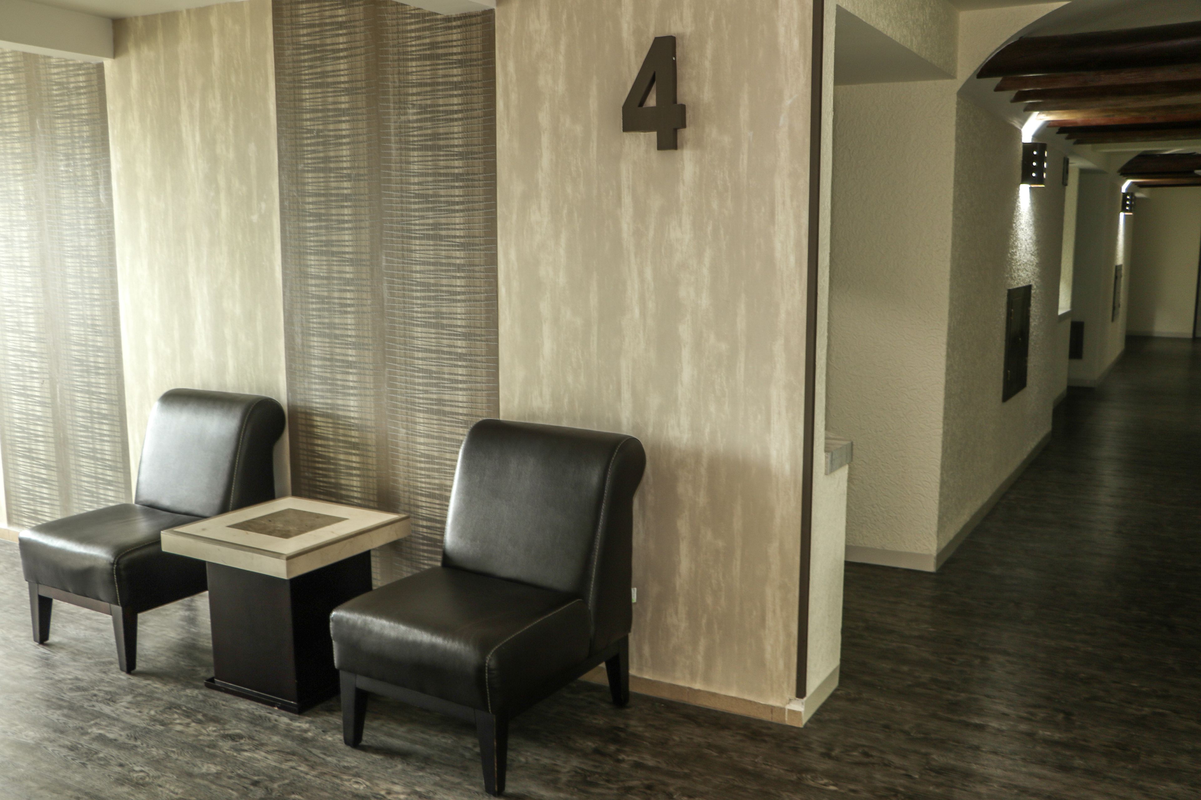 Un moderno vestíbulo de hotel con dos sillones de cuero, una mesita y el número 4 colgado en la pared.