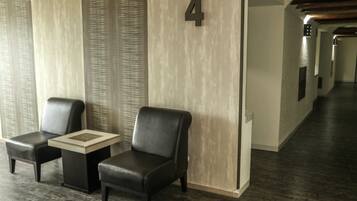 Un moderno vestíbulo de hotel con dos sillones de cuero, una mesita y el número 4 colgado en la pared.