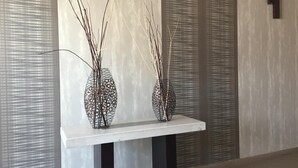 Two vases with tall, thin branches on a white table against a textured wall. - Hotel La Luna (Mexico City)