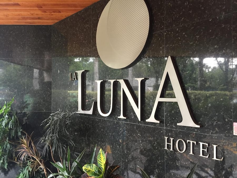 A sign for Luna Hotel with a modern design and indoor plants.