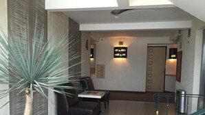 A hotel lobby with a reception desk, seating area, and a staircase. - Hotel La Luna (Mexico City)