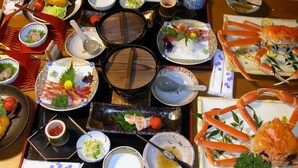 A table with various dishes, including seafood and vegetables, arranged for a meal. - Minshuku Jinya (Fukui)