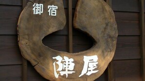 A wooden crescent-shaped sign with Japanese characters. - Minshuku Jinya (Fukui)