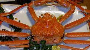 A crab on a plate with a garnish, surrounded by a table setting. - Minshuku Jinya (Fukui)