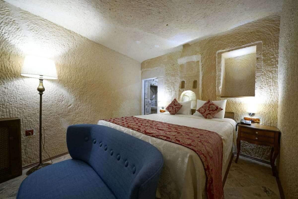A bedroom with a bed, a blue chair, a lamp, and a nightstand.