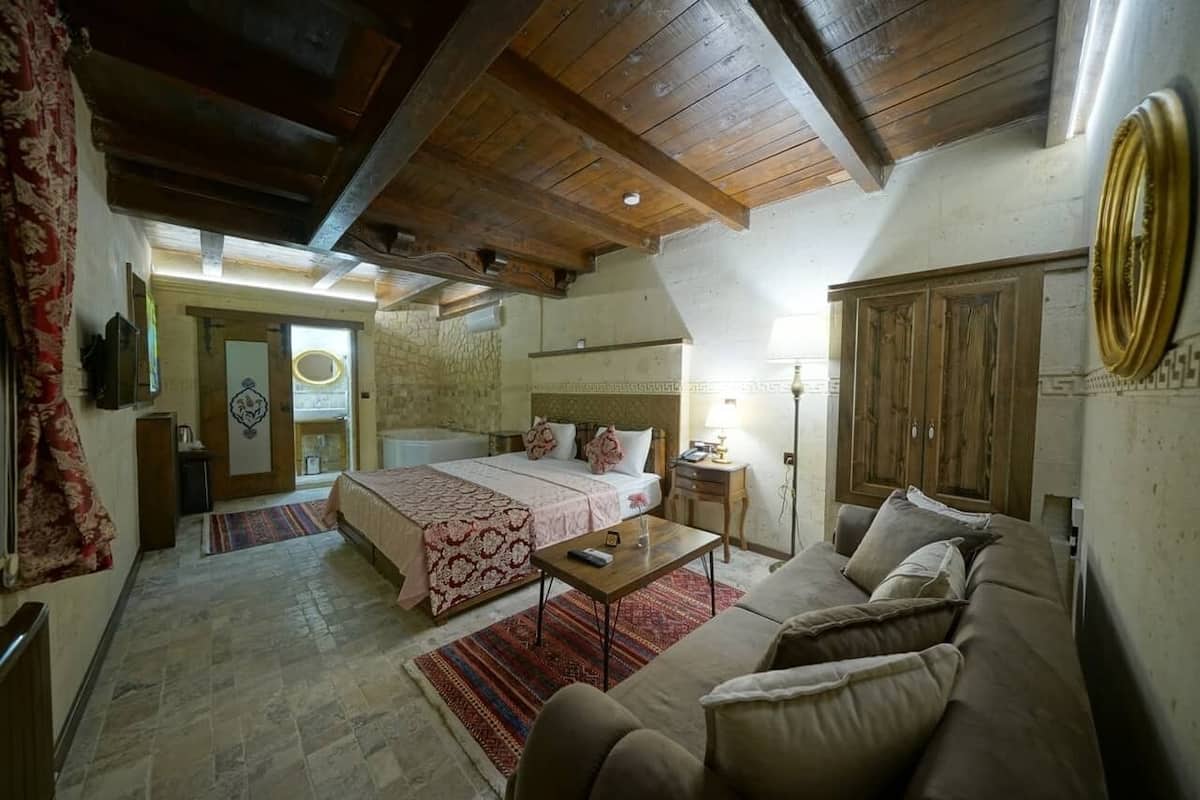 A bedroom with a bed, a wooden ceiling, a nightstand, and a lamp.