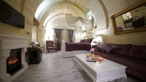 A spacious living room with a fireplace, a television, a sofa, and a coffee table. - Arte Cave Hotel (Ürg üp)
