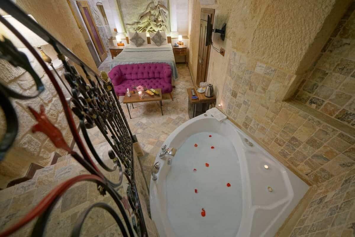 A bathroom with a bathtub, a purple sofa, and a small table with a lamp.