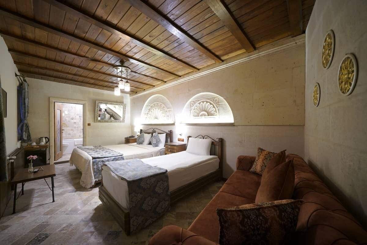 A room with two beds, a sofa, a small table, and decorative wall elements.
