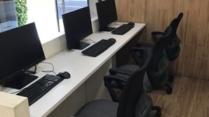 Un espace de travail comprenant trois bureaux d’ordinateur, chacun équipé d’un écran, d’un clavier et d’une souris. Il y a deux chaises de bureau. La pièce est dotée d’un plancher en bois et d’une grande fenêtre.