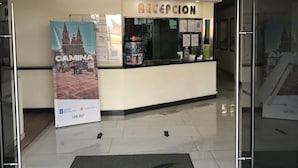 Un comptoir d’accueil avec une enseigne au-dessus, une affiche sur le mur et des flèches directionnelles peintes sur le sol.