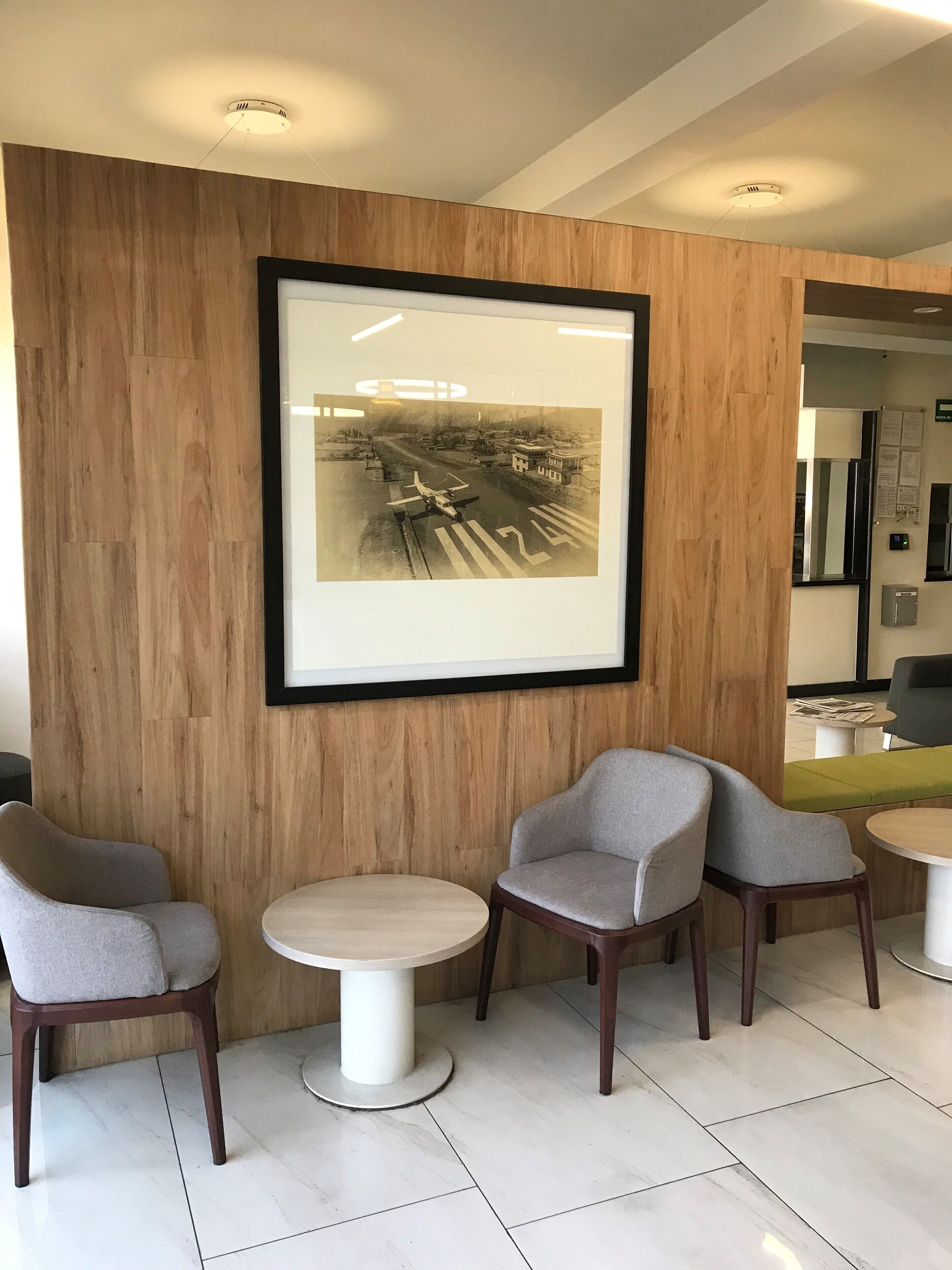 Un intérieur moderne avec des murs lambrissés en bois, une photographie en noir et blanc encadrée et un espace salon avec des tables et des chaises rondes.