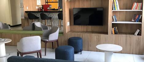 Una sala de estar moderna con sofá, sillones, pufs, televisor y estantería.