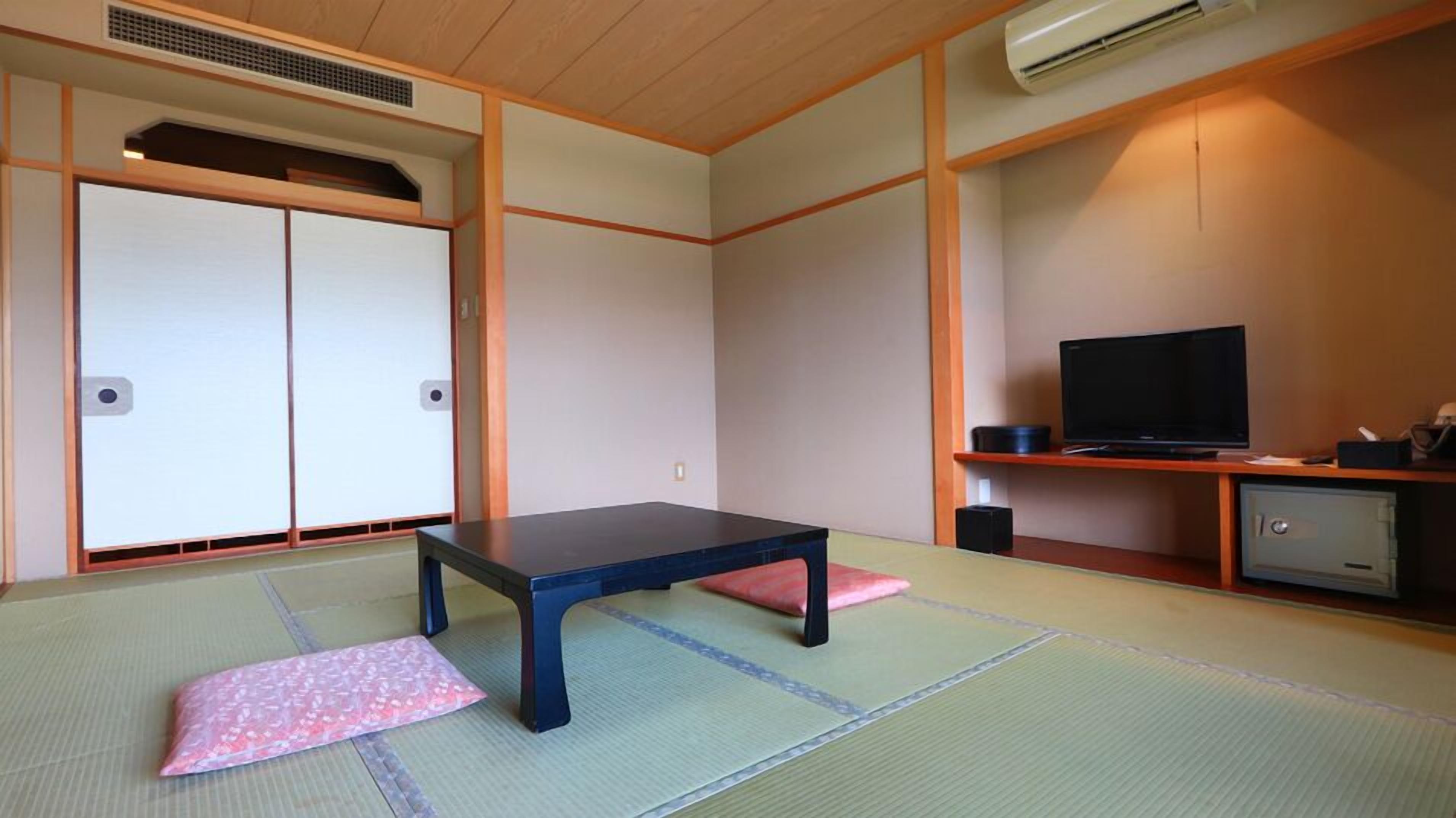 Ein traditioneller japanischer Raum mit Tatami-Böden, einem niedrigen Tisch, einem Fernseher und einem Schrank.