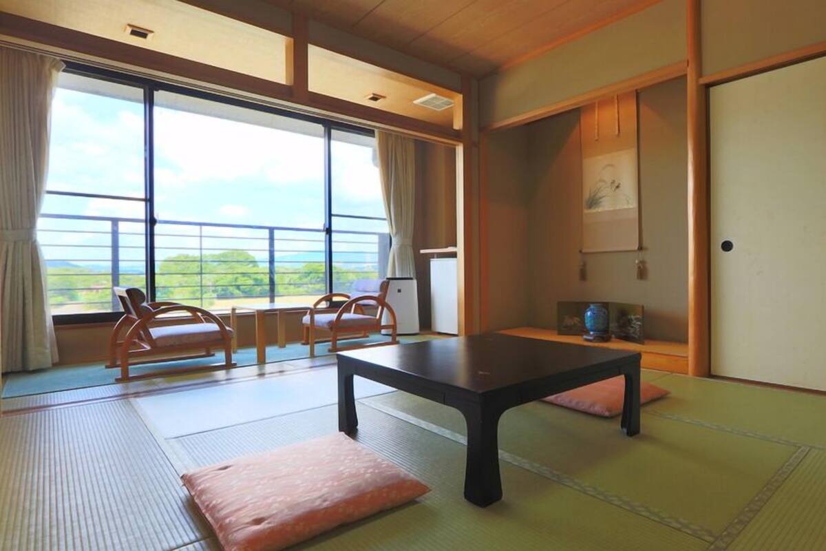 A traditional Japanese room with tatami flooring, a low table, and sliding doors.