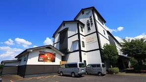 A building with a white facade and black trim, two parked vans, and a clear blue sky.