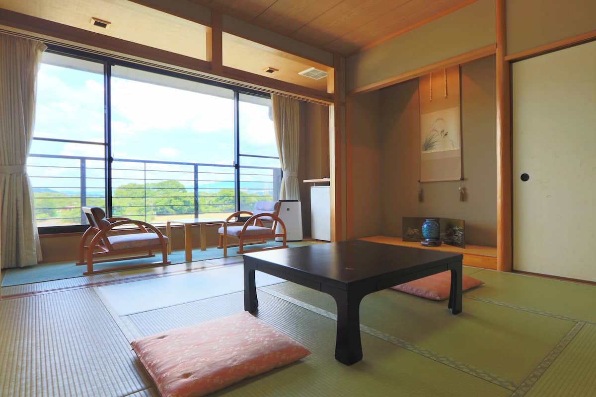 A traditional Japanese room with tatami flooring, a low table, and a view of the outdoors.