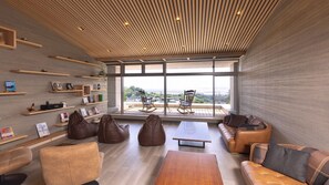 Una sala de estar moderna con techo inclinado, estantes empotrados, un ventanal con vistas y asientos cómodos.