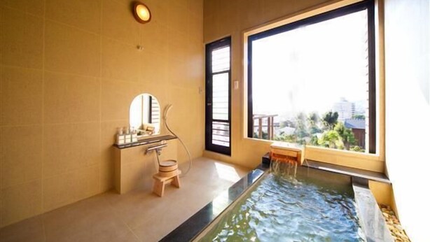 A bathroom with a large window, a bathtub, and a small wooden stool. - Kannawa Onsen Zekkei No Yado Sakuratei (Beppu)