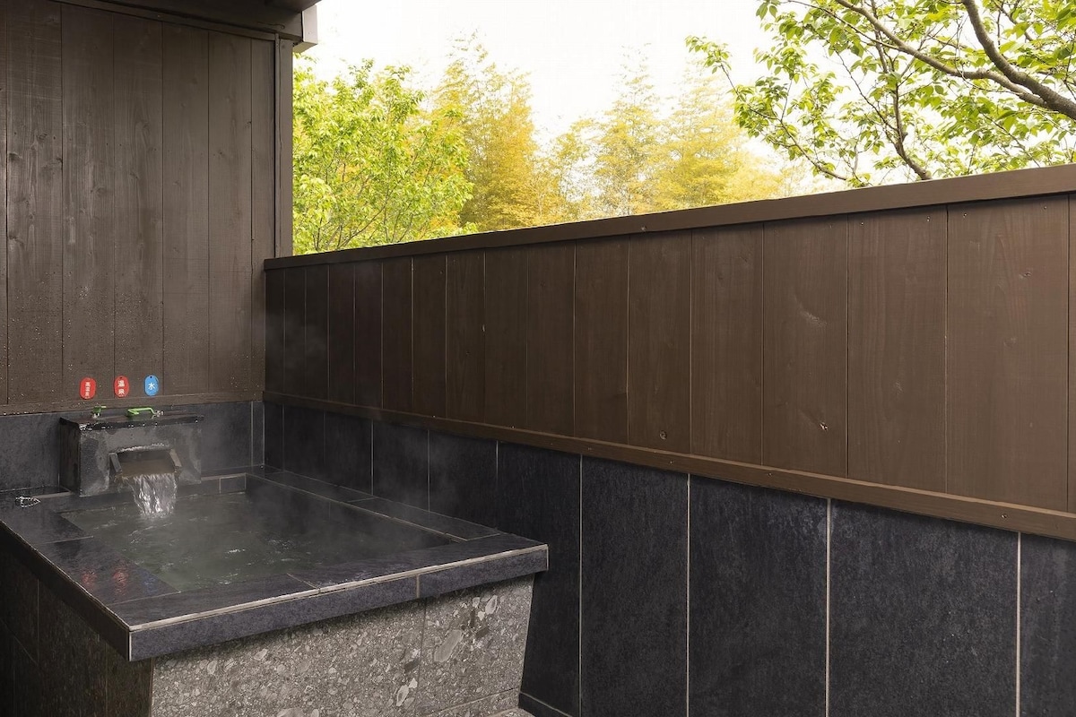 A hot tub with a stone base, surrounded by dark wooden walls and a tiled floor.