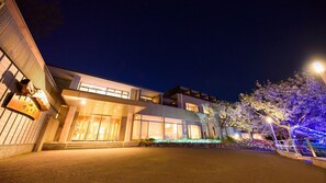 A modern building with a flat roof, large windows, and a well-lit entrance.