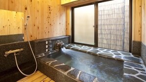 A wooden spa room with a stone hot tub, a wooden bench, and a sliding glass door leading outside. - Kannawa Onsen Zekkei No Yado Sakuratei (Beppu)