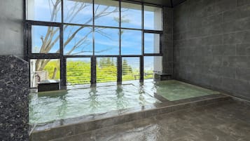 Een spa ruimte met een groot raam, een badkuip en uitzicht op groen.