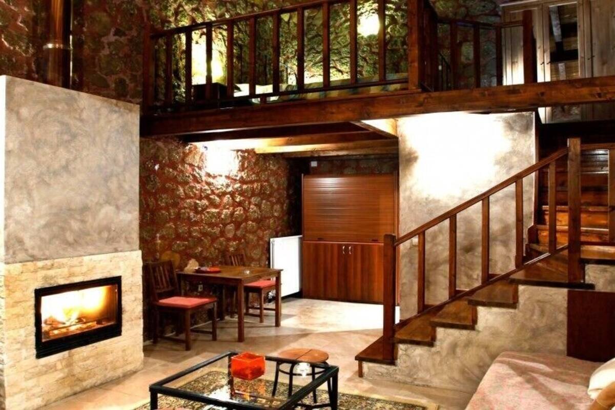 Ein gemütliches Interieur mit Kamin aus Stein, einer Holztreppe und einem Essbereich.