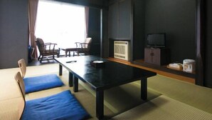 A tatami mat room with a low table, chairs, a television, and a window. - Hosenji Onsen Ryusenkaku (Kokonoe)