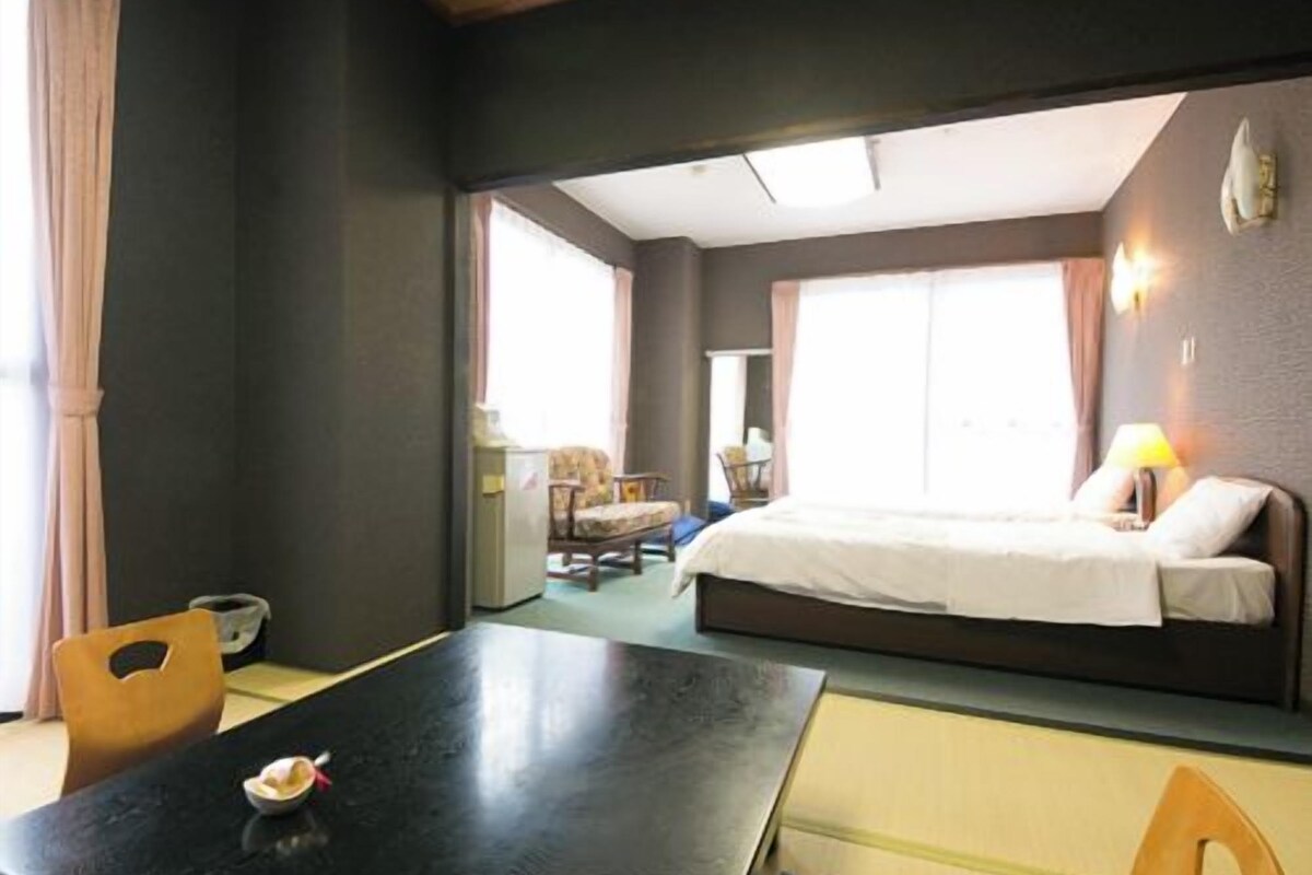 Habitación de hotel con cama, una mesa de comedor y vista a otra habitación.