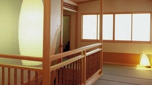 A traditional Japanese room with tatami flooring, a wooden staircase, and a large paper lantern. - Yuraku (Misasa)