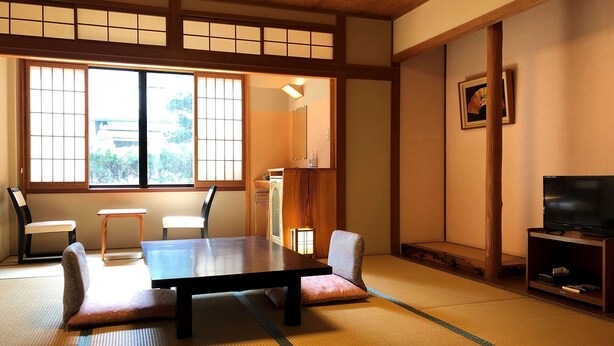 A traditional Japanese room with tatami flooring, a low table, and sliding doors. - Yuraku (Misasa)
