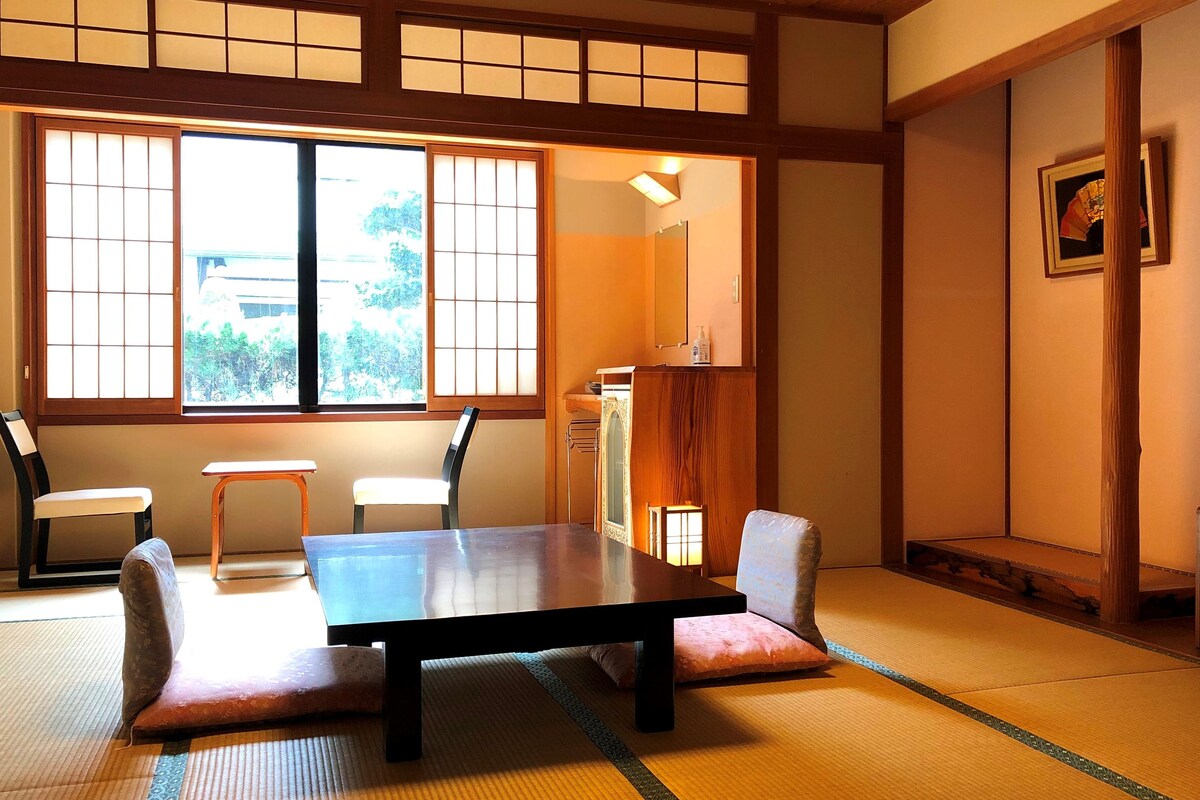 Ein traditioneller japanischer Raum mit Tatami-Böden, einem niedrigen Tisch und einem Fernseher.