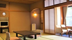 A traditional Japanese room with tatami flooring, a low table, and seating. - Yuraku (Misasa)