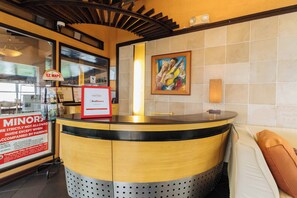 A reception area with a counter, a painting on the wall, and a sign indicating a minor parking restriction. - Reddoorz Plus @ The Ridge Tagaytay City (Tagaytay)