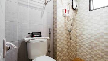 Une petite salle de bain avec des toilettes, une douche et un mur carrelé.