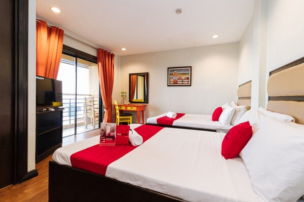 A hotel room with two beds, a TV, a desk, and a window with curtains. - Reddoorz Plus @ The Ridge Tagaytay City (Tagaytay)